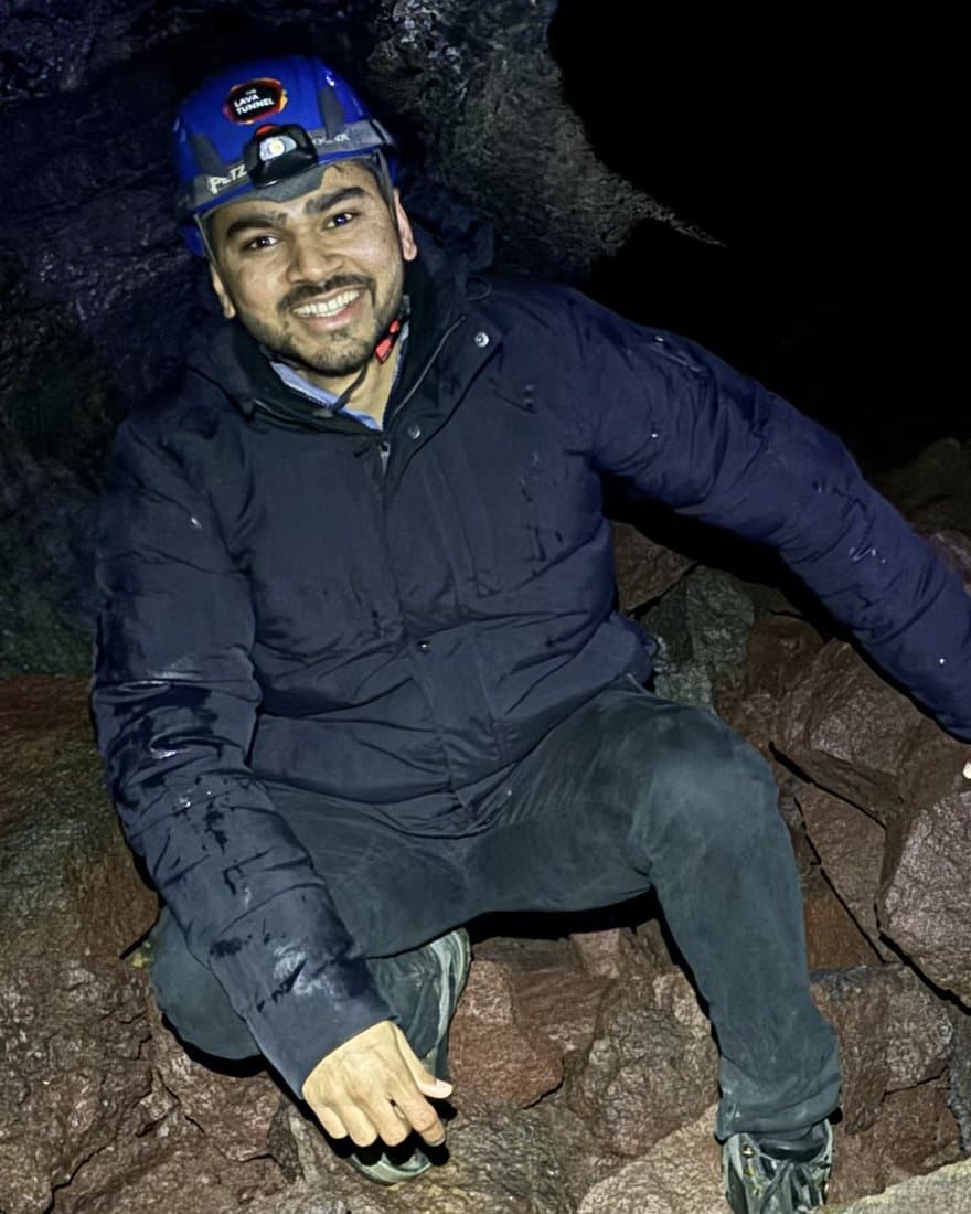 Akash Patel inside a lava tube in Iceland, wearing a helmet and headlamp